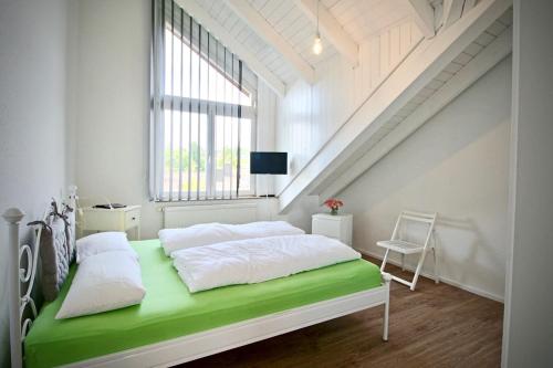 a white bedroom with a green bed and a staircase at Maisonette Alpenblick in Überlingen