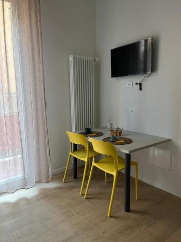 a dining room with a table and yellow chairs at Calari Rooms - Affittacamere in Bologna