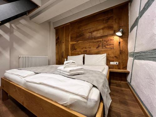 een slaapkamer met een groot bed en een houten muur bij Goldbachmühle Fewo Kornhaus in Überlingen