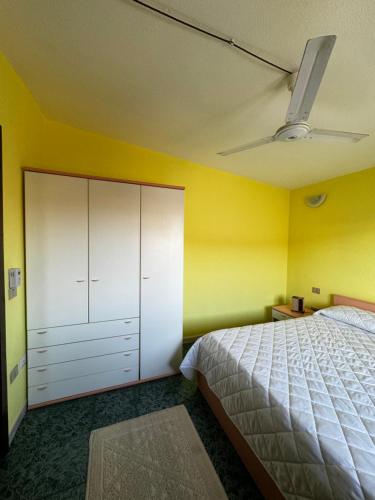 um quarto com uma cama branca e uma parede amarela em Berchida 1 em La Caletta