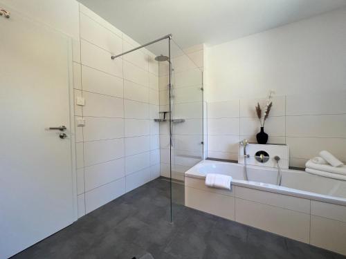 a bathroom with a tub and a glass shower at Ferienwohnung am Tobelbach in Überlingen
