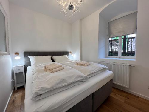 a white bedroom with a large bed with two towels on it at Bodensee-Liebe in Überlingen