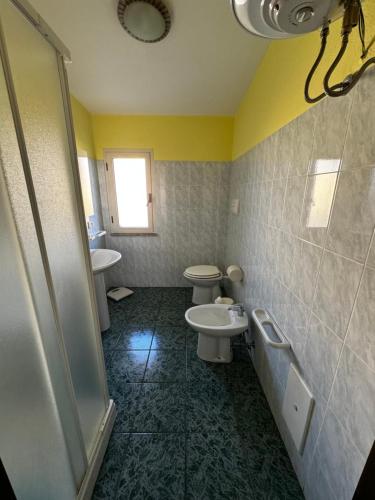 uma casa de banho com 2 WC, um lavatório e um chuveiro em Berchida 1 em La Caletta