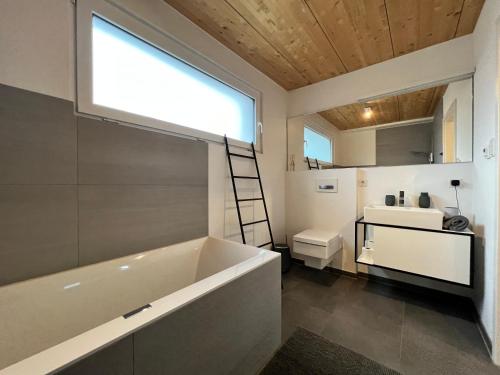 een badkamer met een groot bad en een wastafel bij STAY in Uhldingen-Mühlhofen