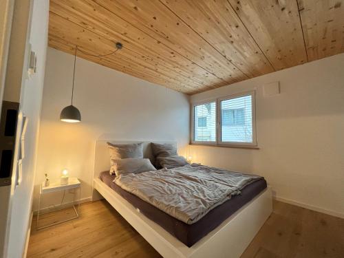 een bed in een kamer met een houten plafond bij STAY in Uhldingen-Mühlhofen