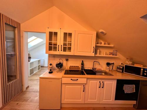 une cuisine avec des armoires blanches et un évier dans l'établissement Lecomte, à Oissel