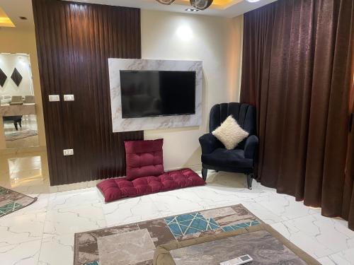 a living room with two chairs and a flat screen tv at شقة فندقية غرفتين للايجار بالمهندسين in Cairo