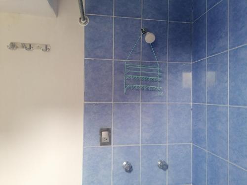 een blauwe betegelde douche met een groen handdoekenrek bij Habitación cómoda y tranquila in Mexico-Stad