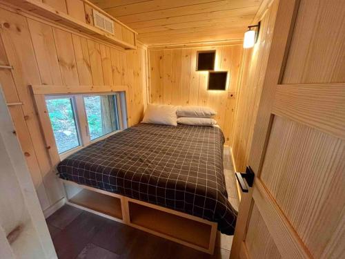 Cette chambre en bois comprend un petit lit et une fenêtre. dans l'établissement Cabin Zoobox 79, à Eastman