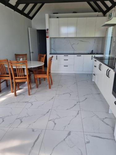 a kitchen with white cabinets and a table and chairs at Lakeview Colonial House in Queenstown