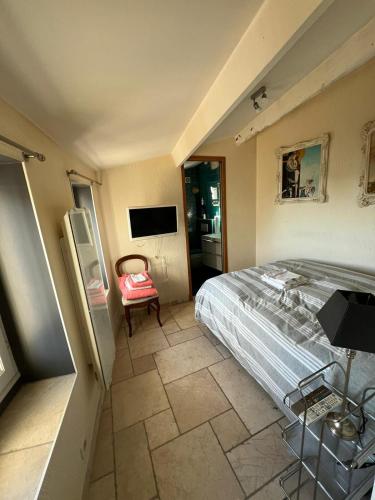 une chambre avec un lit, une télévision et une chaise dans l'établissement Maison de 6 pièces au coeur du village d'Eze, à Èze