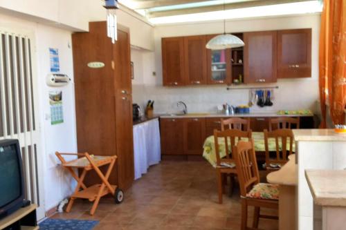 eine Küche mit Holzschränken sowie einem Tisch und Stühlen in der Unterkunft 2 bedrooms property with shared pool at Porto Cesareo 1 km away from the beach in Porto Cesareo