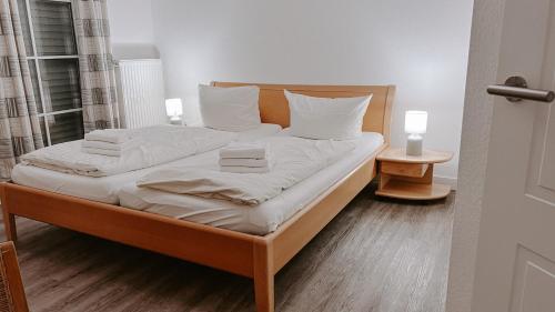 een bed met witte lakens en kussens in een kamer bij "Deichmöwe" im Möwennest Greetsiel in Krummhörn