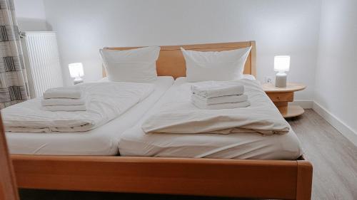 een slaapkamer met 2 bedden met witte lakens en kussens bij "Deichmöwe" im Möwennest Greetsiel in Krummhörn