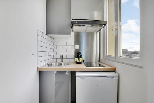 une petite cuisine avec un évier et une fenêtre dans l'établissement Appartement Suite 41 aux Portes de Paris, à Aubervilliers