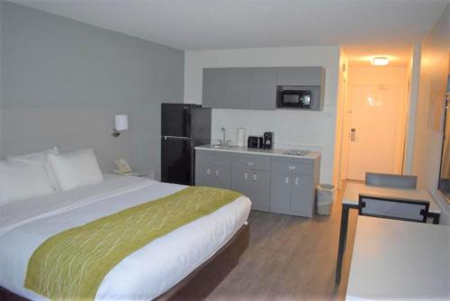a hotel room with a bed and a kitchen at MainStay Suites MSP Airport - Mall of America in Bloomington