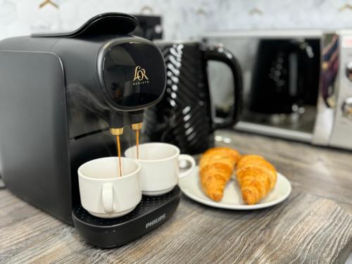 Una cafetera está haciendo tazas de café con cruasanes en Modern One-Bedroom Apartment en Swindon