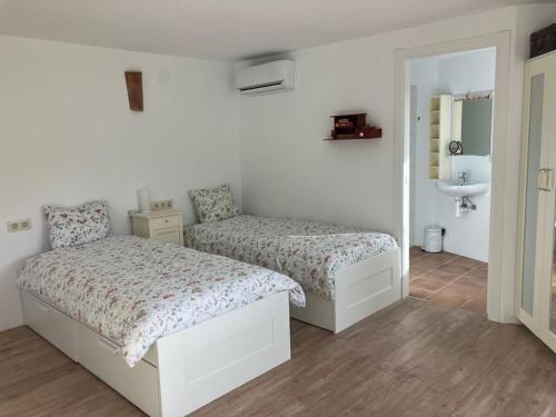 1 dormitorio blanco con 2 camas y lavamanos en La Peñita - sunny guesthouse with private pool and garden, en Salobreña