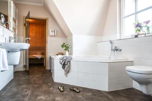 een badkamer met een bad, een wastafel en een toilet bij Haus Rose, Luxus-Ferienhaus in Fuhlendorf fur 4 Personen in Fuhlendorf