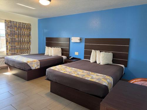 a hotel room with two beds and a blue wall at American Inn Punta Gorda in Punta Gorda
