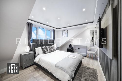 Hackney Suites - En-suite rooms & amenities في لندن: غرفة نوم بيضاء مع سرير ومكتب