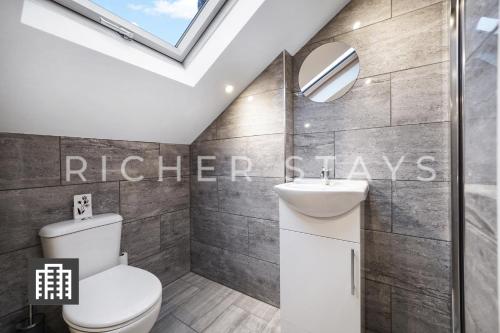 a bathroom with a toilet and a sink and a skylight at Hackney Suites - En-suite rooms & amenities in London