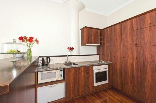 a kitchen with wooden cabinets and a counter top at Life on Water- Princes Wharf apartment with fabulous views in Auckland