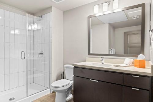 La salle de bains est pourvue de toilettes, d'un lavabo et d'une douche. dans l'établissement Stunning Westgate CozySuites by stadium with pool 5, à Glendale