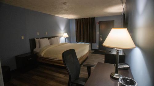 una camera d'albergo con letto e tavolo con lampada di Ashley Motel a Plainfield