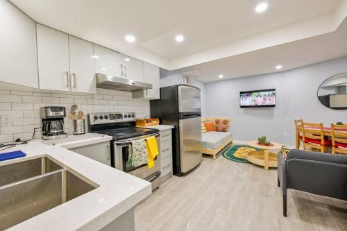 a kitchen with stainless steel appliances and a living room at Stylish 2BR: w/free parking & streaming! in Pickering