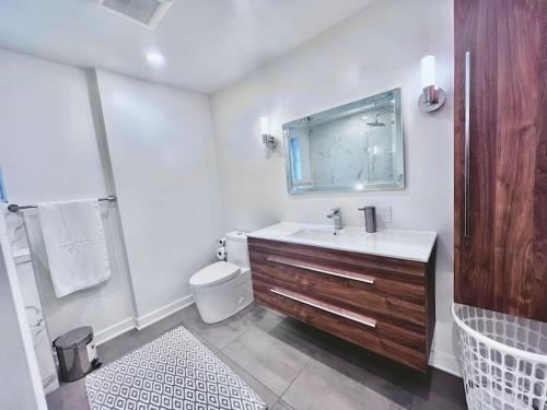 La salle de bains blanche est pourvue d'un lavabo et de toilettes. dans l'établissement Cozy haven near Olympic Park, Pac-Man Arcade Game, à Montréal