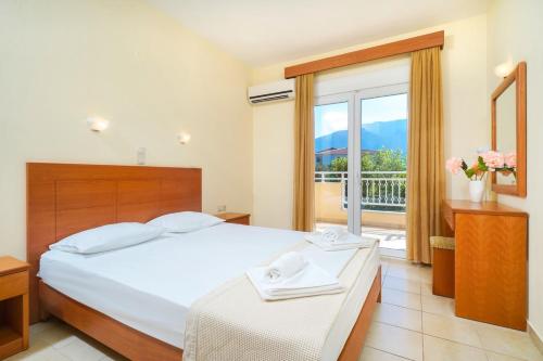 a bedroom with a large bed and a balcony at Ladikas apartments in Chrysi Ammoudia