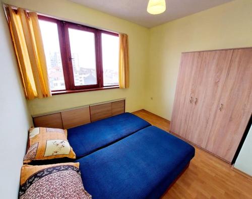 - une chambre avec un lit bleu et une fenêtre dans l'établissement Cozy apartment with top view, Wi-Fi & parking, à Stara Zagora
