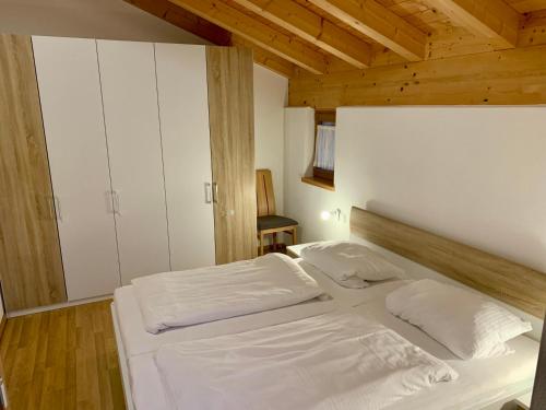 uma cama branca num quarto com tecto em madeira em Feriendorf Via Claudia Ferienhaus Martin em Lechbruck