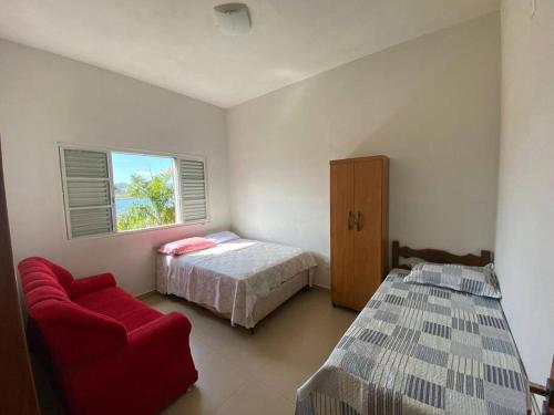 - une chambre avec un lit et un canapé rouge dans l'établissement Rancho em Capitólio-MG, à Capitólio