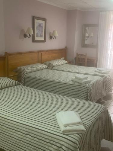 three beds in a hotel room with towels on them at La Posá in Villar del Arzobispo