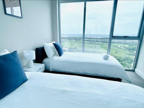 two beds in a room with a large window at Panoramic City View 3bedroom condo Wi-Fi Parking in Sydney
