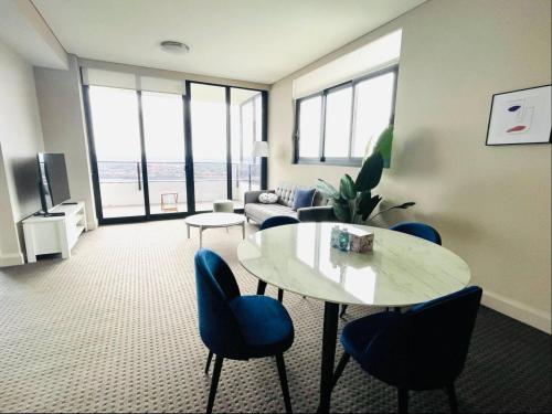 a living room with a table and blue chairs at Panoramic City View 3bedroom condo Wi-Fi Parking in Sydney