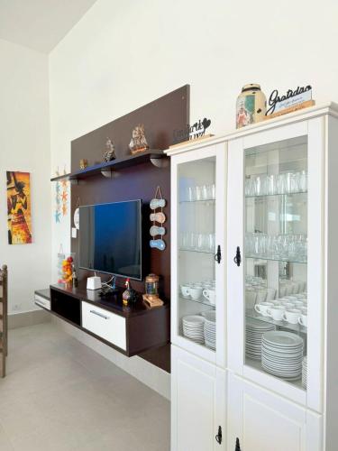 a dining room with a white cabinet filled with dishes at Pousada Village Cozumel in Guarujá