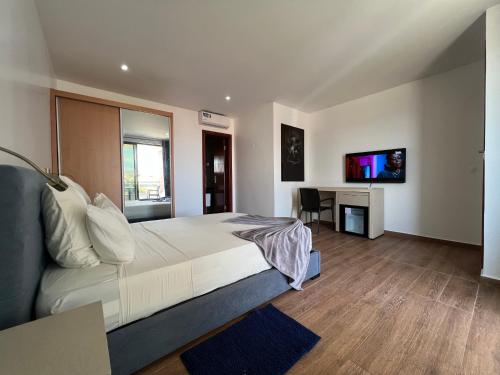 um quarto com uma cama, uma secretária e uma televisão em Lali's House em Tarrafal