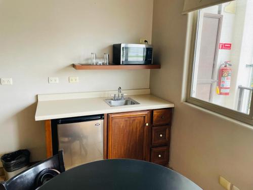 a small kitchen with a sink and a microwave at Hotel las Palmas in Hermosillo