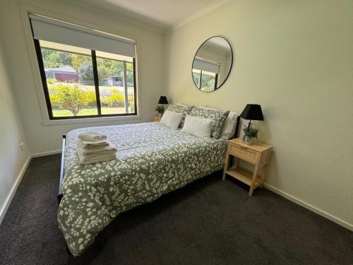 a bedroom with a bed and a mirror and a window at Belford House in Myrtleford