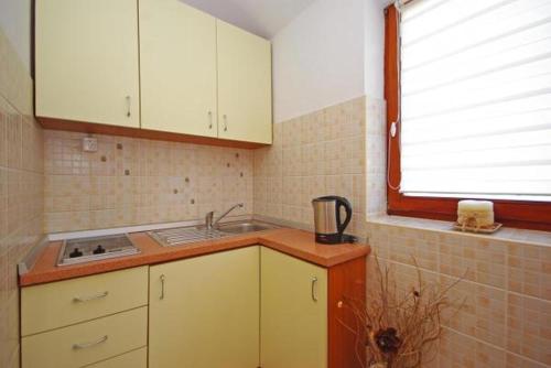 d'une cuisine avec des placards blancs, un évier et une fenêtre. dans l'établissement Apartment in Zaton (Zadar) with sea view, loggia, air conditioning, Wi-Fi (4810-4), à Zaton
