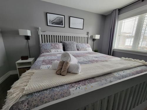 Un dormitorio con una cama con un osito de peluche. en Le Cozy Clover, en Moncton