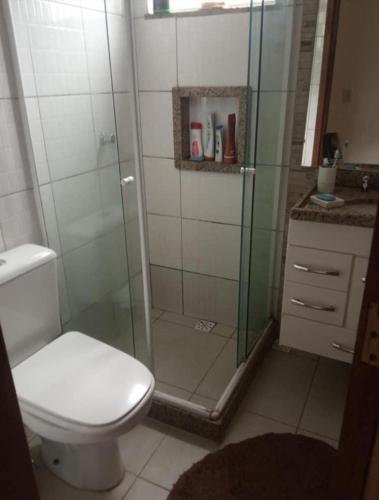 a bathroom with a toilet and a glass shower at Casa a 40 minuto da praia in Rio de Janeiro