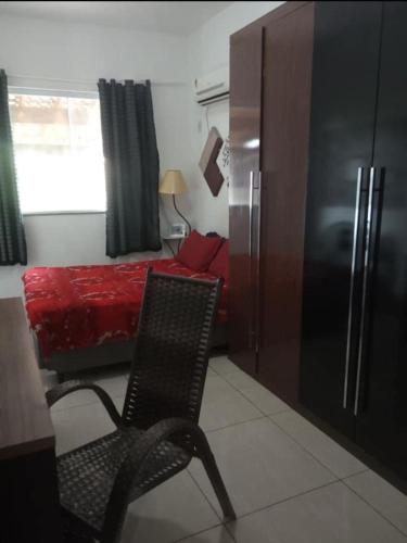 um quarto com uma cadeira, uma cama e um frigorífico em Casa a 40 minuto da praia no Rio de Janeiro