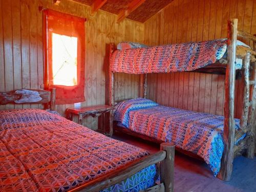 a bedroom with two bunk beds and a window at Cabaña El artesano Puyehue in Ñilque