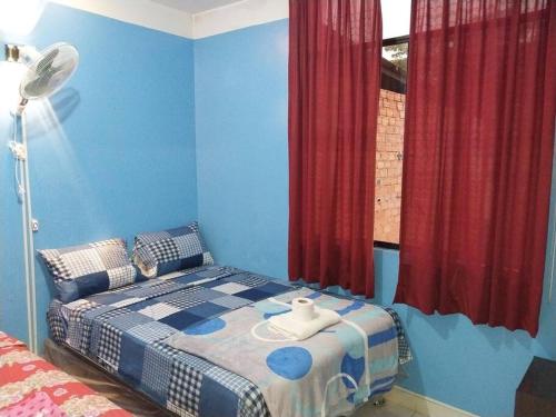 1 dormitorio con 1 cama con paredes azules y cortinas rojas en Hospedaje EDUCOL en Moyobamba
