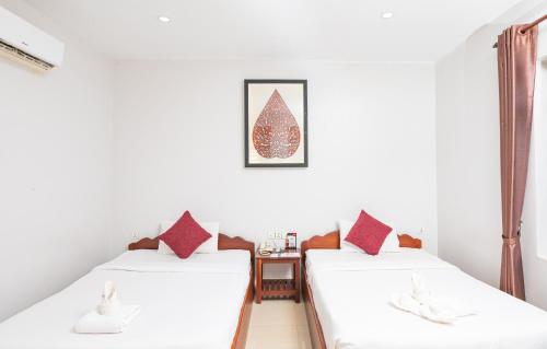 two beds in a room with white walls and red pillows at Damnak Soksan Hotel in Siem Reap