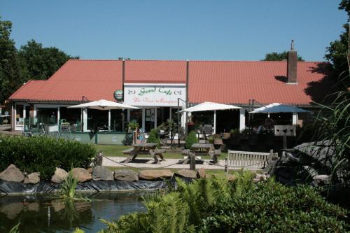 a restaurant with a building and a pond in front of it at Stacaravan 130 De Tien Heugten in Schoonloo